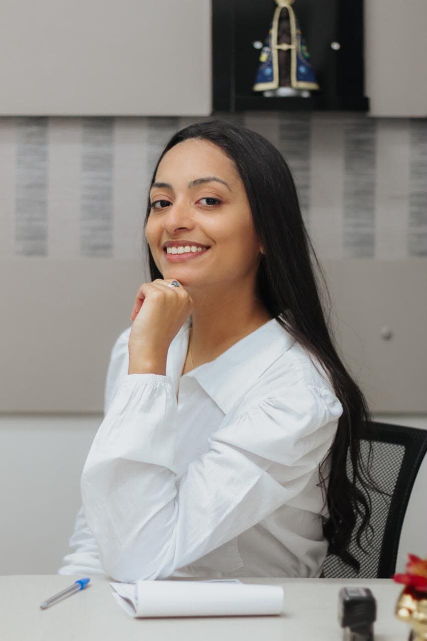 Dra. Iana Guedes sentada à mesa do consultório da Odonto Casais